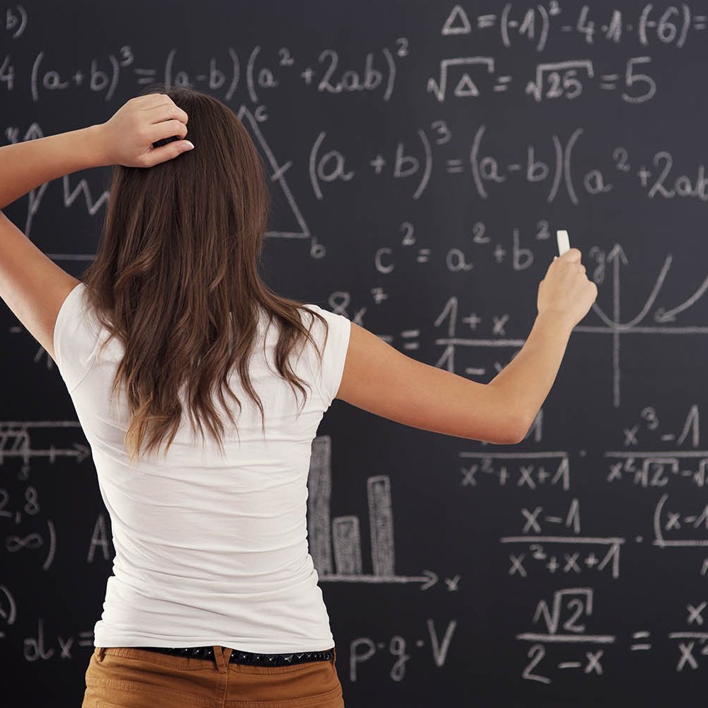 Young woman looking at math problem on blackboard
